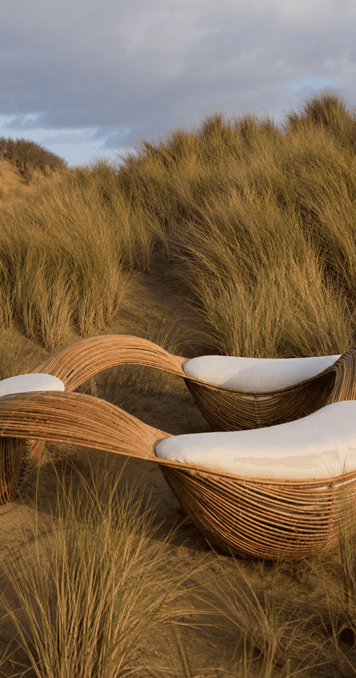 Woven rattan lounge chairs in dune grass
