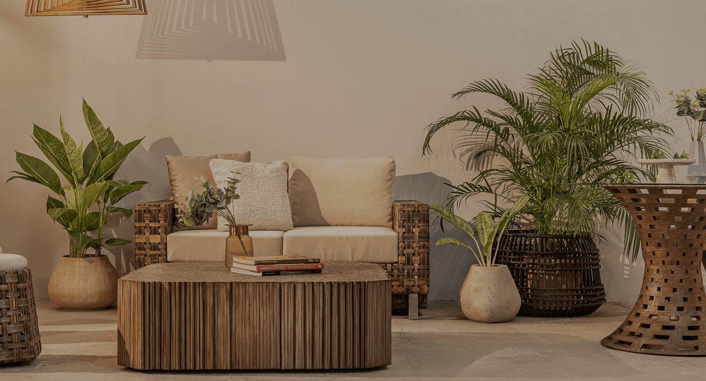 Styled living room set with a lounge sofa, fluted coffee table, woven side tables, and planters