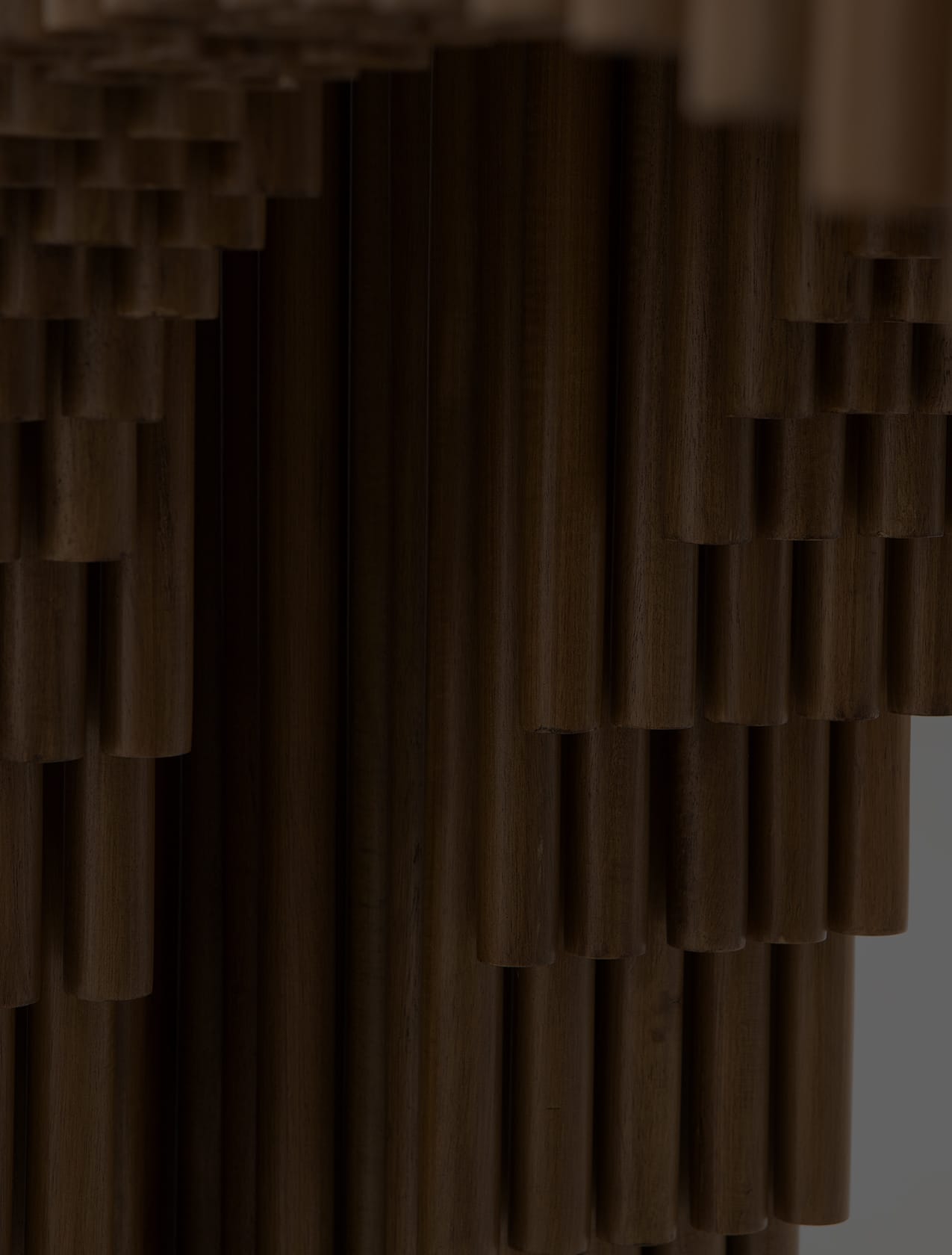 Close view of a stepped screen built from densely packed dark wooden dowels