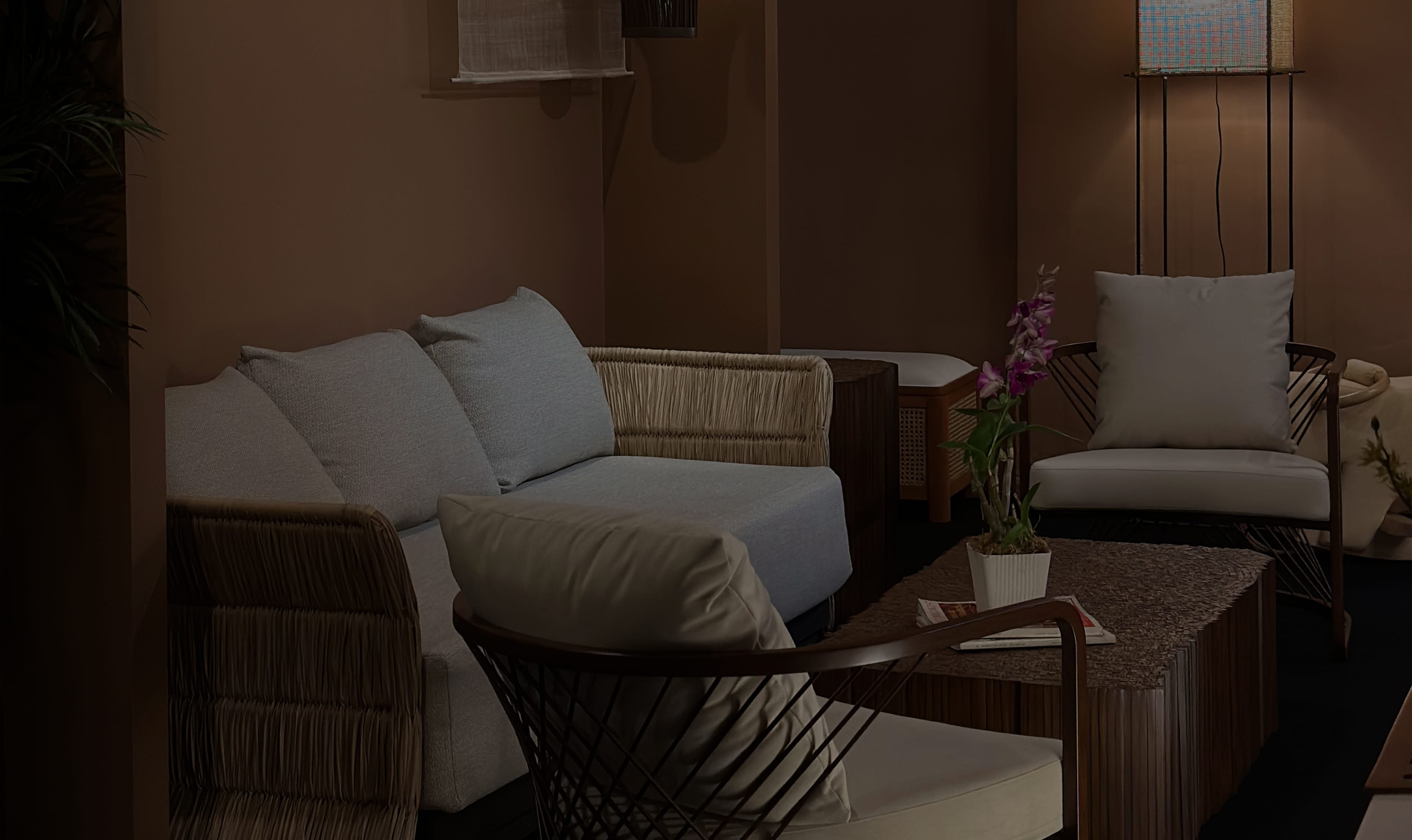 Makati showroom seating vignette with a pale blue sofa, fringed woven armchairs, and an orchid on a stone-topped table