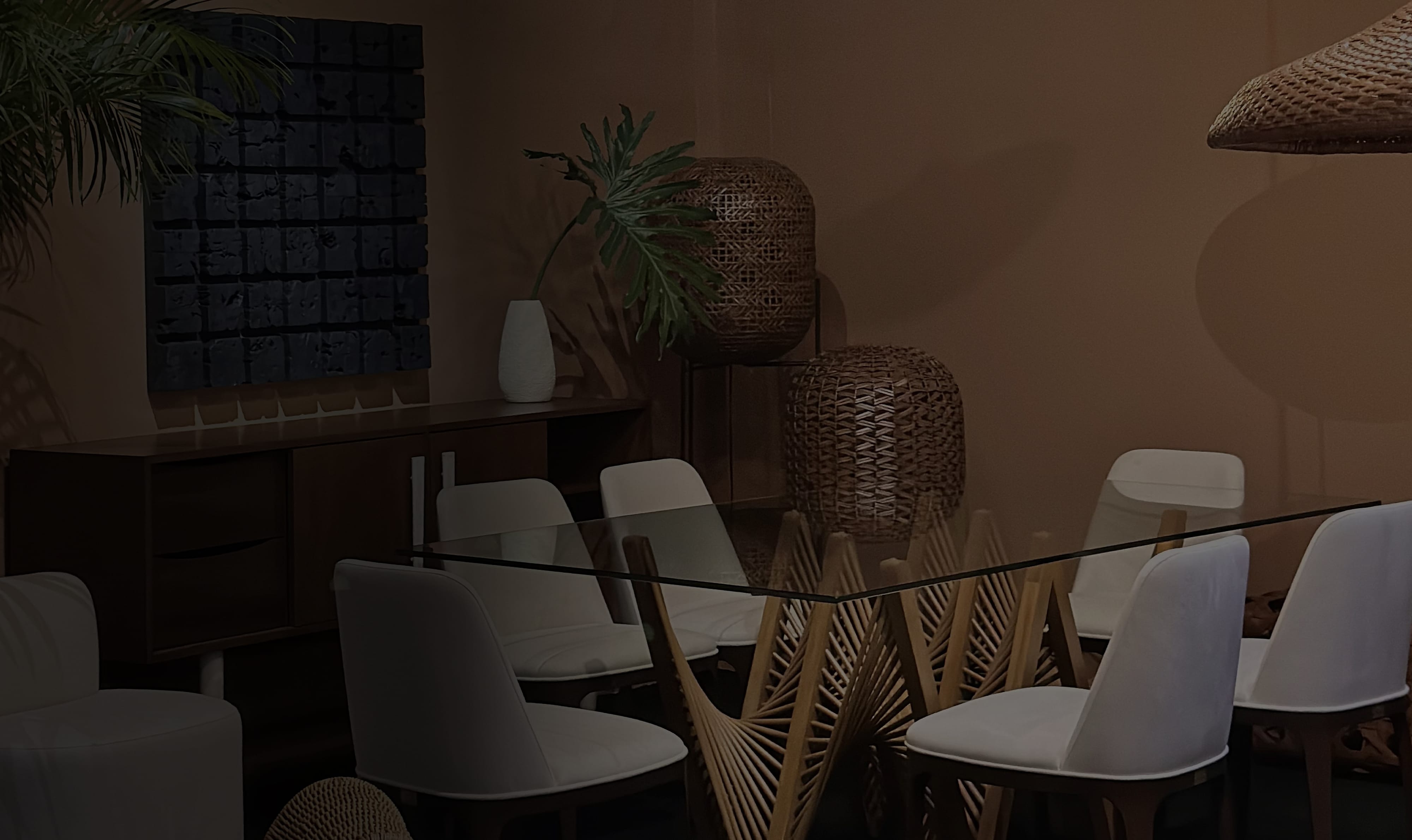 Makati showroom dining setting with a glass-topped table on a fanned rattan base, white chairs, and woven pendant lanterns