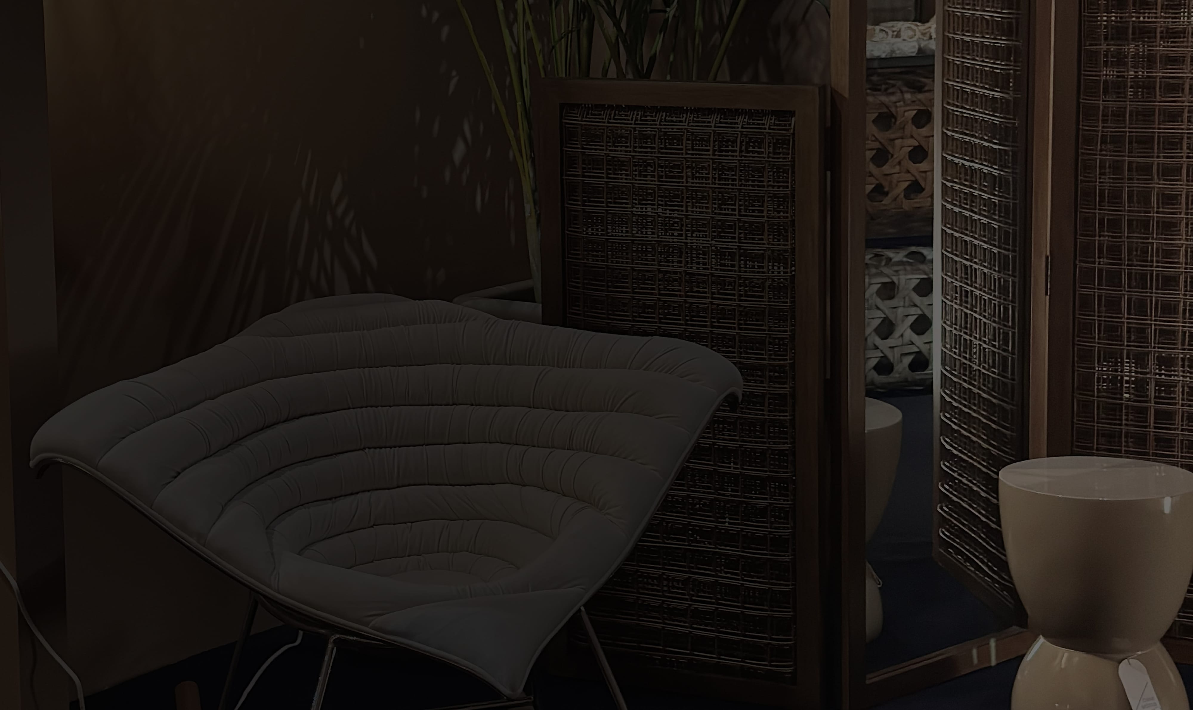 Makati showroom lounge chair with a quilted pale cushion beside dark woven folding screens