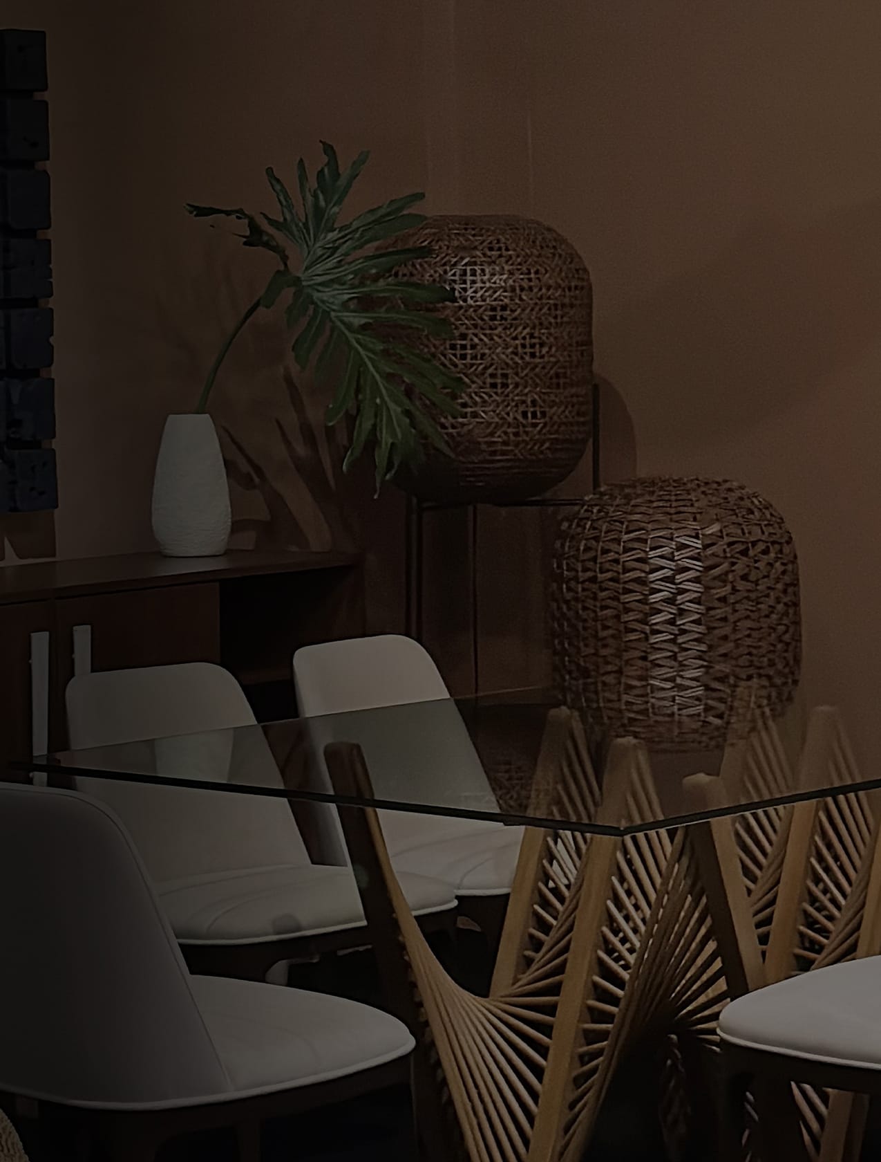 Makati showroom dining setting with a glass-topped table on a fanned rattan base, white chairs, and woven pendant lanterns