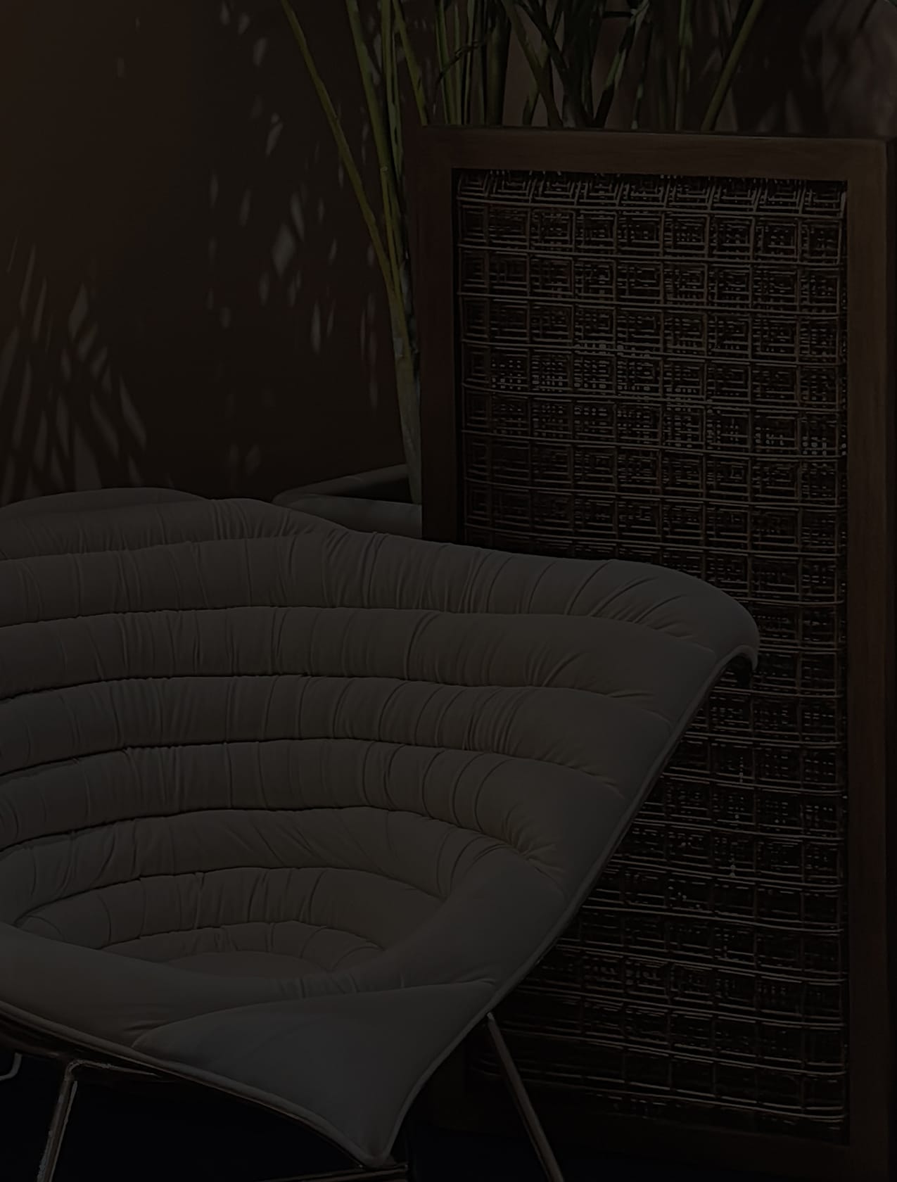 Makati showroom lounge chair with a quilted pale cushion beside dark woven folding screens